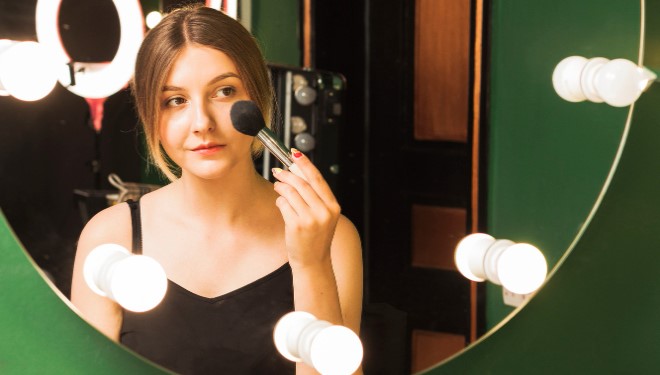 Maquillaje de mujer con espejo iluminado de hotel.